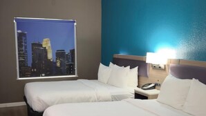 A hotel room with two beds, a cityscape view, a nightstand with a phone, and a blue accent wall. - Comfort Inn San Antonio Northeast (San Antonio)