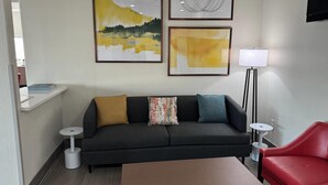 A modern living room with a sofa, a red chair, a coffee table, and two framed artworks on the wall. - Comfort Inn San Antonio Northeast (San Antonio)