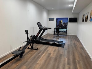 Un gimnasio en casa con cinta de correr, elíptica y mancuernas.