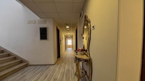 Ein Flur mit einer Holztreppe, einem Schminktisch mit Spiegel und einer Tür am Ende.