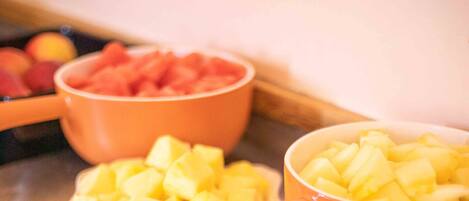 Una mesa de buffet con diversos platos de fruta, como piña y mango.