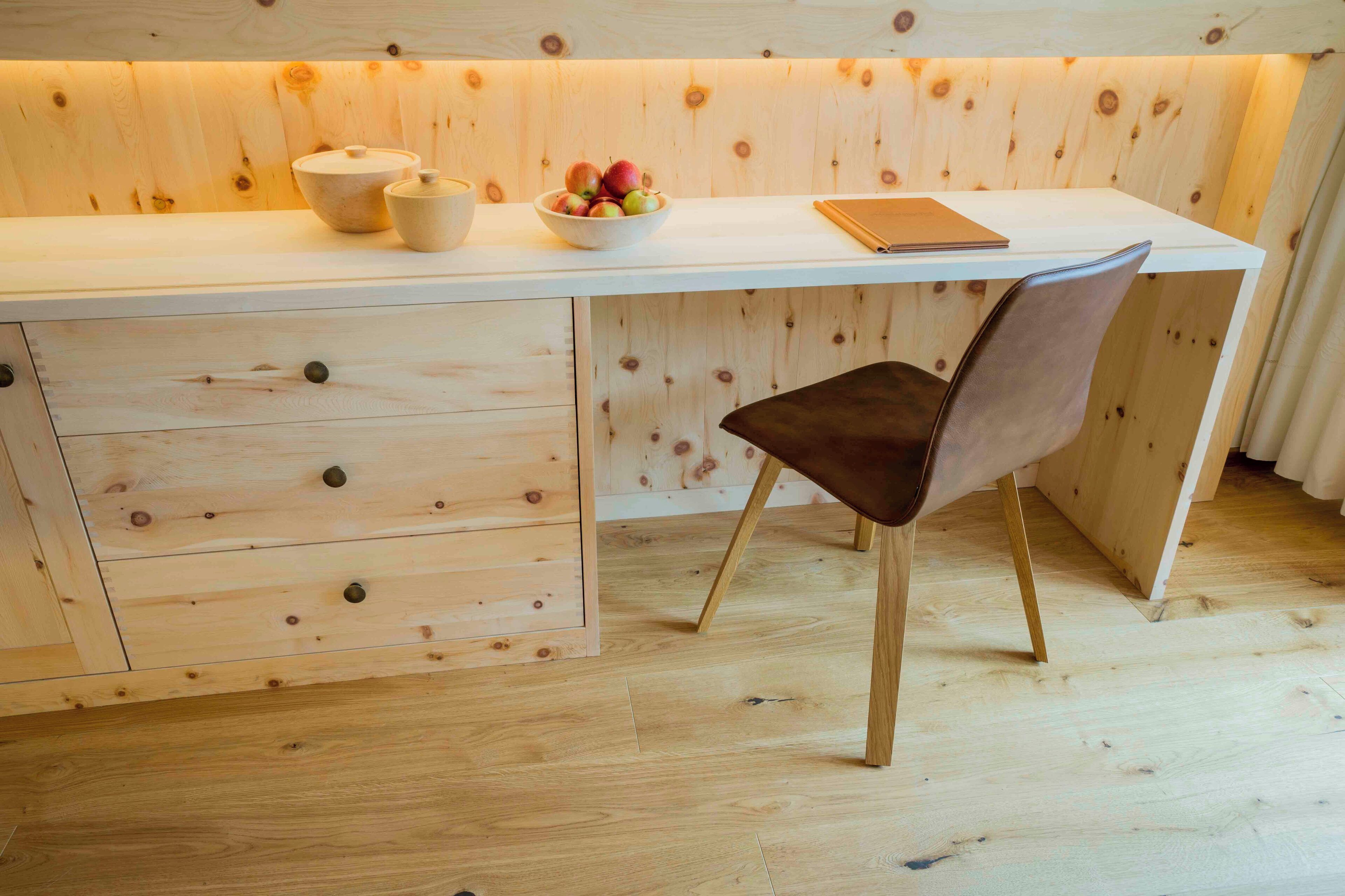 Een houten bureau met een schaal fruit, een notitieboekje en een beker.