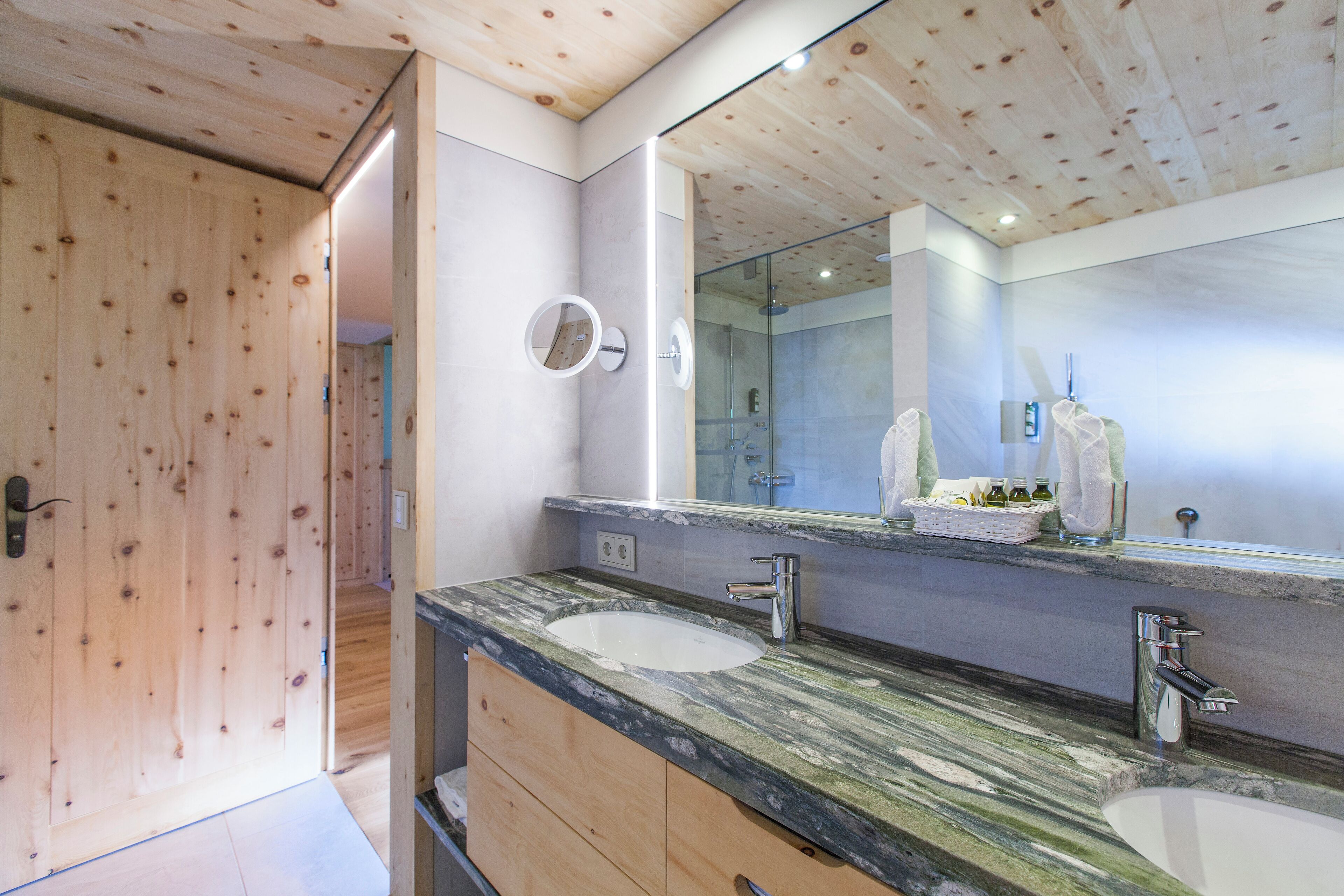 A bathroom with wooden ceiling, two sinks, and a large mirror.