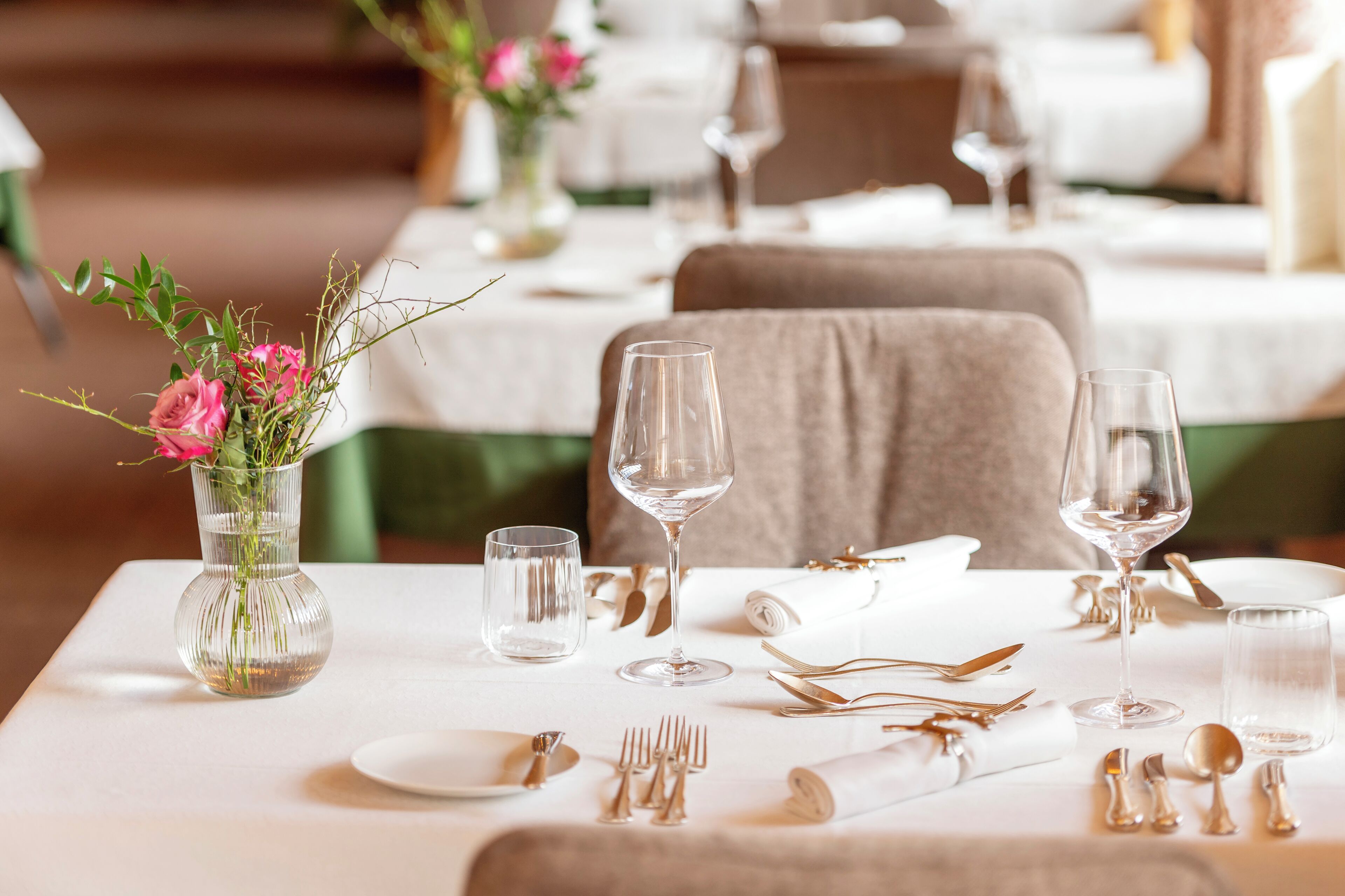 A dining table set with white tablecloth, clear glassware, and neatly arranged cutlery.