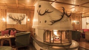 A cozy room with a fireplace, wooden walls, and a mounted deer head. - Montafoner Hof (Tschagguns)