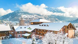 A hotel with a ski lift, wooden buildings, and a snowy mountain backdrop. - Montafoner Hof (Tschagguns)