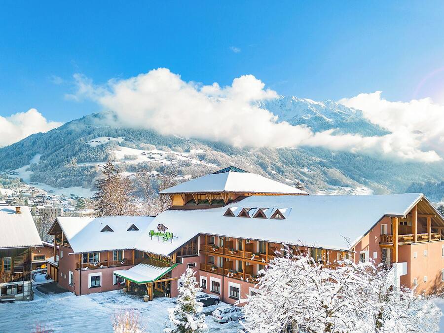 A hotel with a ski lift, wooden buildings, and a snowy mountain backdrop.