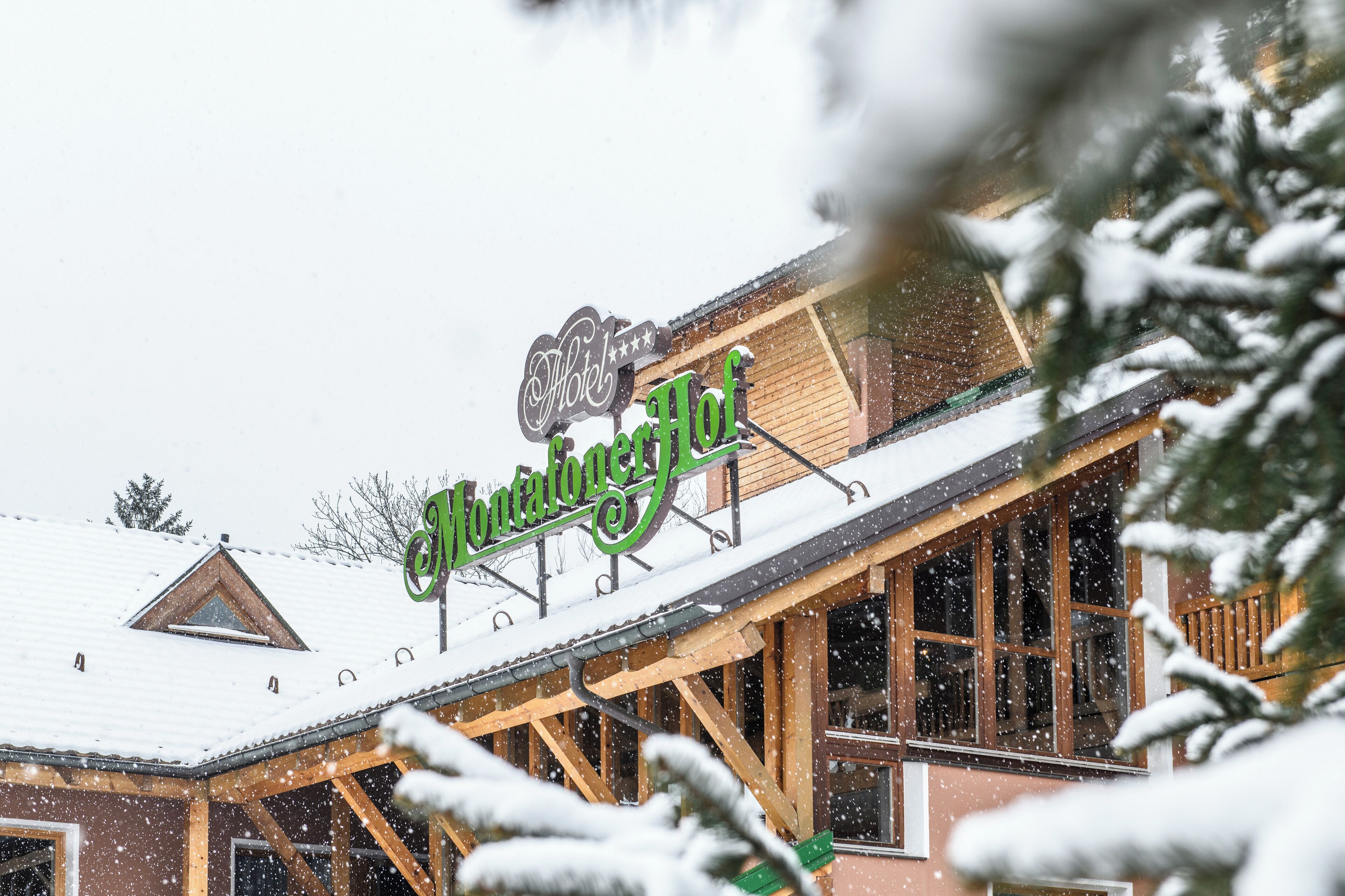Ein Hotelschild mit schneebedecktem Dach und Holzbauweise.