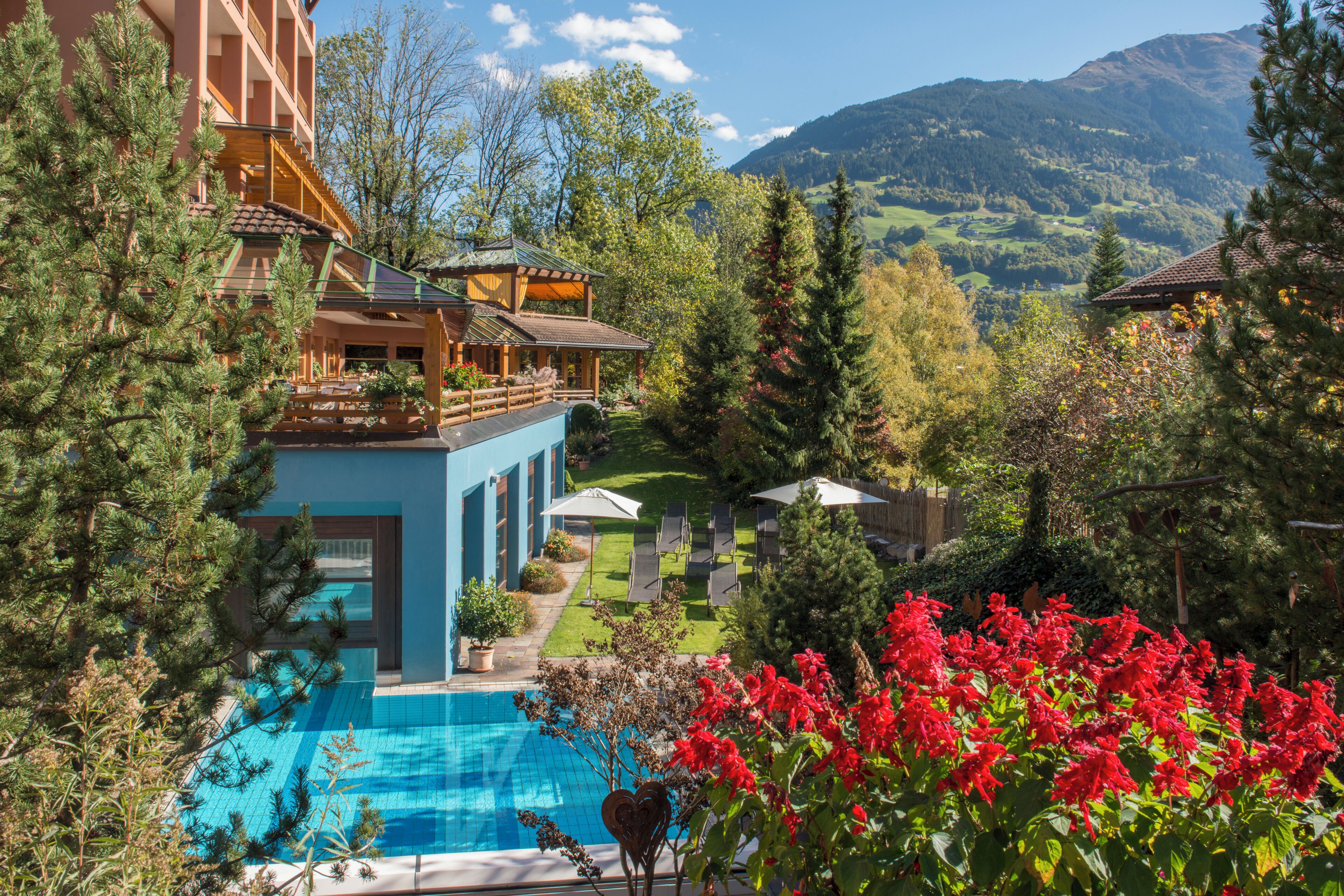 Un hotel con piscina, jardín y vista a la montaña.