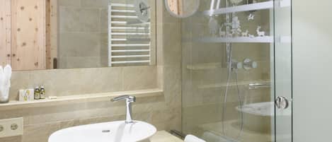 Ein modernes Badezimmer mit einem großem, ovalen Waschbecken, einer Duschkabine aus Glas und einer Holztür.