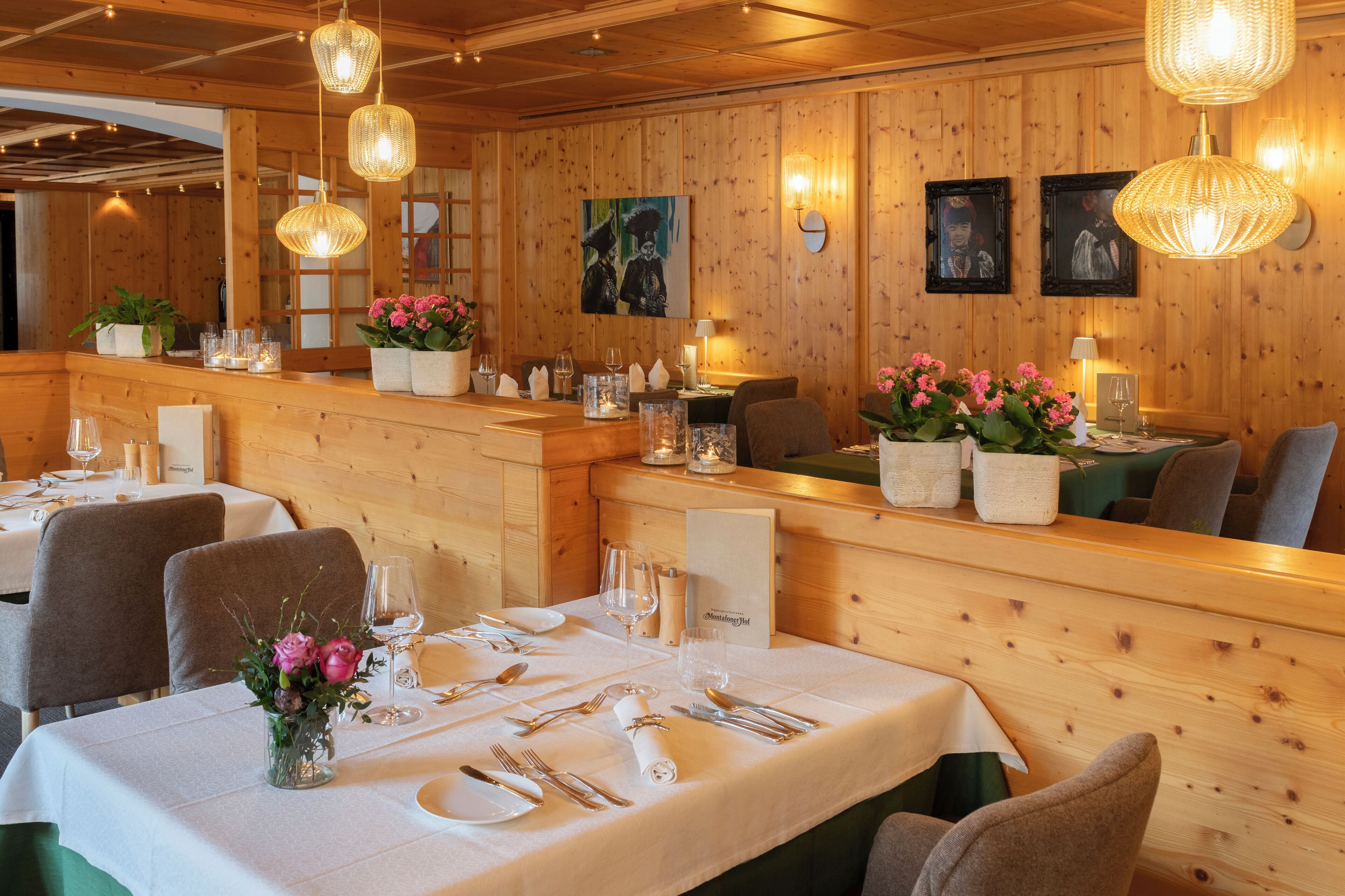 A restaurant with wooden panel walls, hanging wicker light fixtures, and tables set for dining.