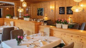 A restaurant with wooden panel walls, hanging wicker light fixtures, and tables set for dining.