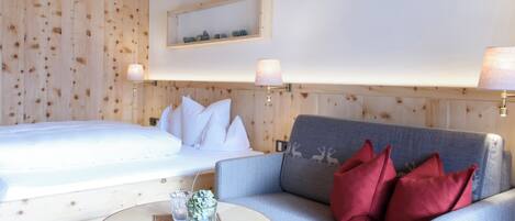 Un dormitorio con una cama, un sofá gris y una mesita de noche con objetos decorativos.
