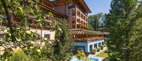 Um hotel com vários andares, varandas, piscina e vegetação exuberante.