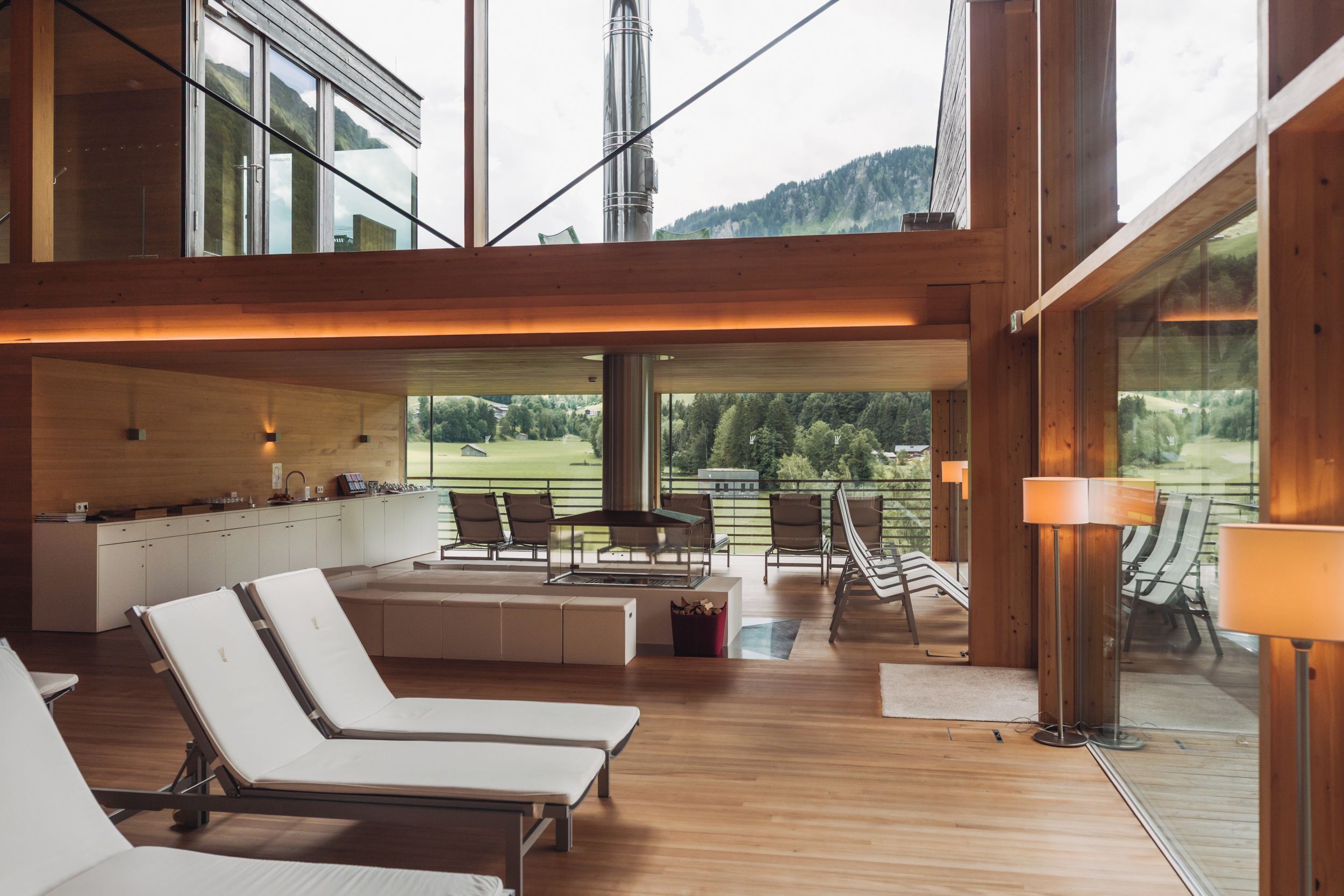 Ein modernes Interieur mit Holzboden, Küchenzeile und einer Sitzecke mit Lounge-Sesseln und Tisch.