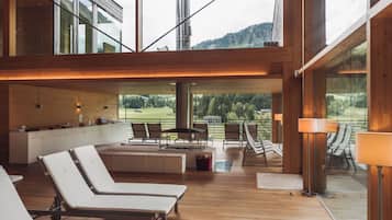 Un intérieur moderne avec un plancher en bois, un coin cuisine et un espace salon comprenant des fauteuils confortables et une table.