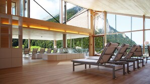A spacious indoor area with large windows offering mountain views, wooden flooring, and several lounge chairs. - Hotel Krone in Au (Au)