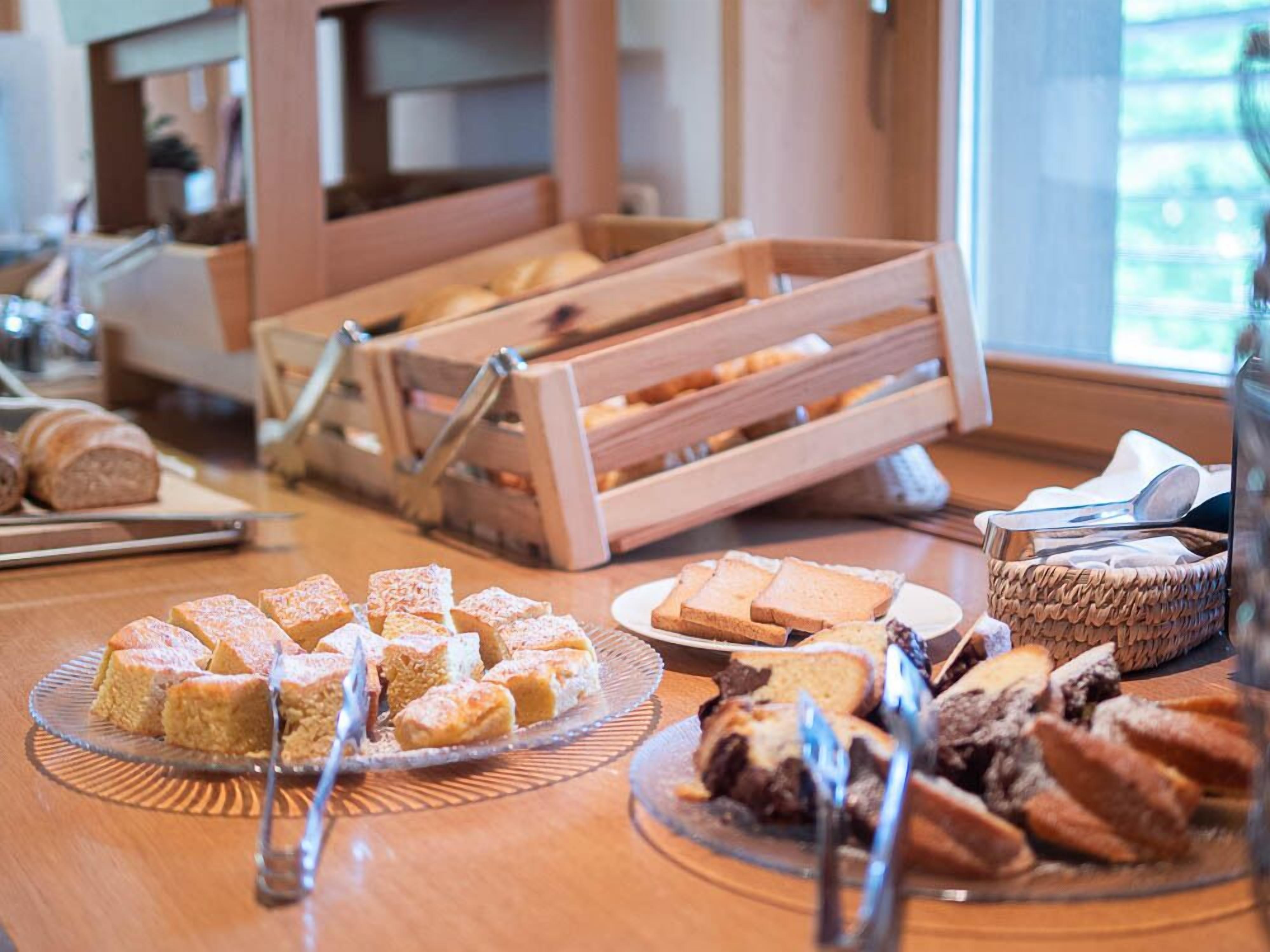 A buffet table with various baked goods, including bread and pastries, arranged on plates and in baskets.