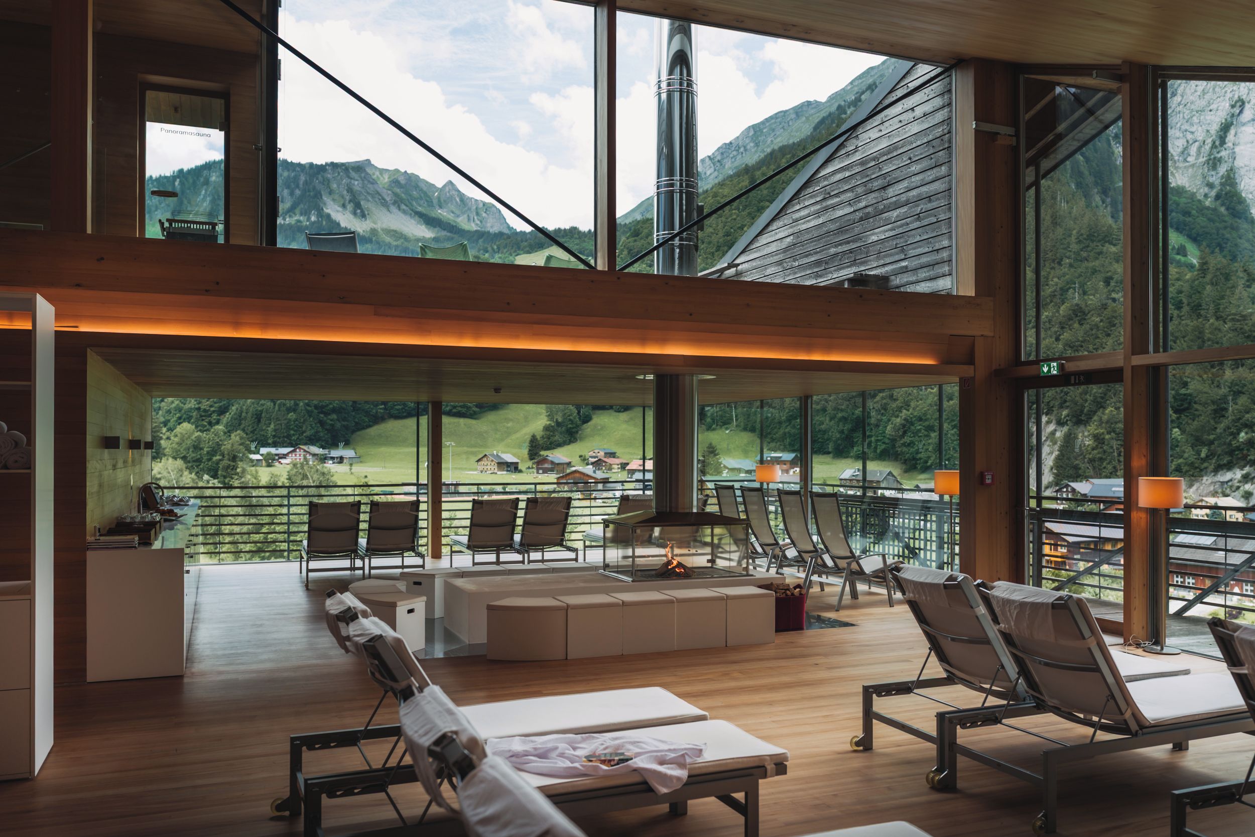 A spacious lounge area with a view of a mountainous landscape through large windows.