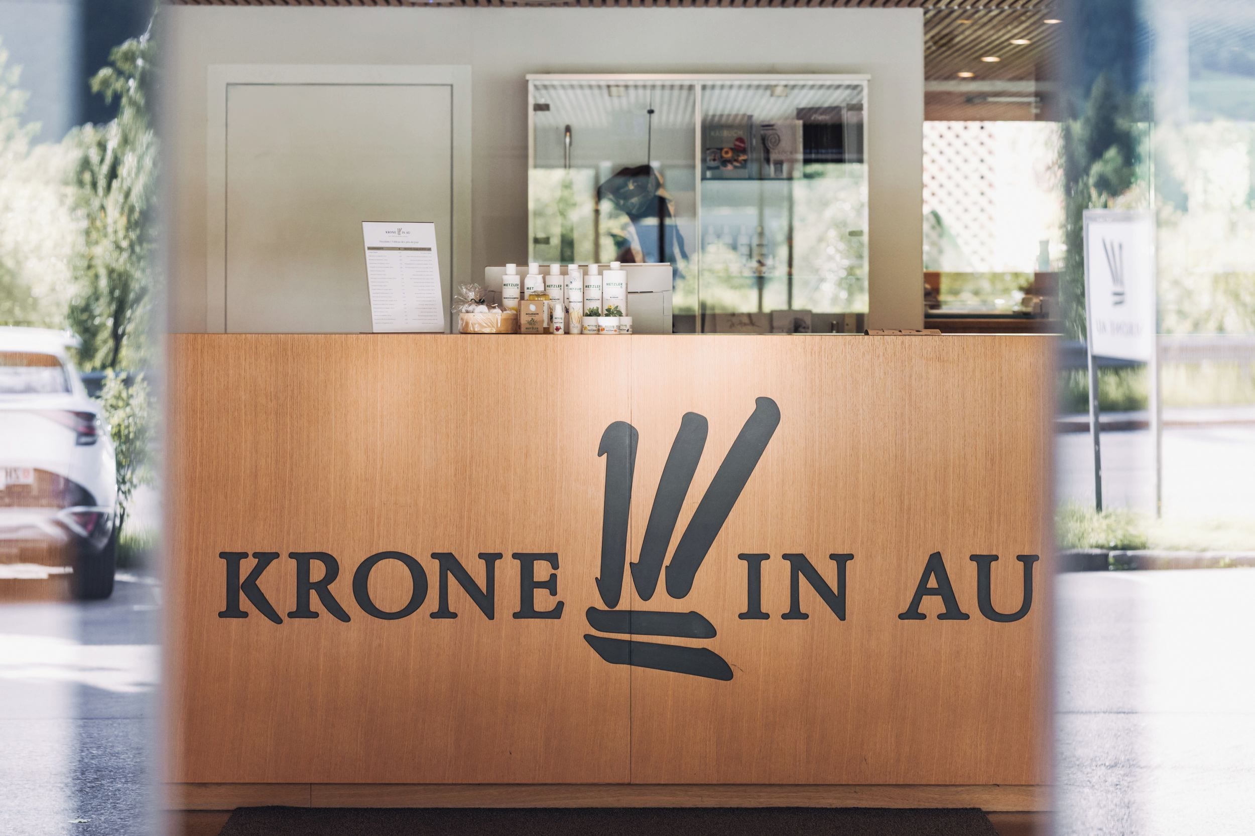Ein hölzerner Empfangstresen mit dem Schriftzug 'KRONE IN AU' und einem Logo.