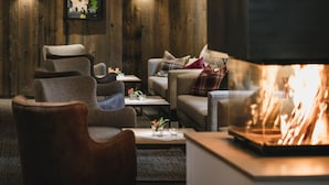 Una sala de estar acogedora con chimenea, paredes de madera y asientos cómodos.