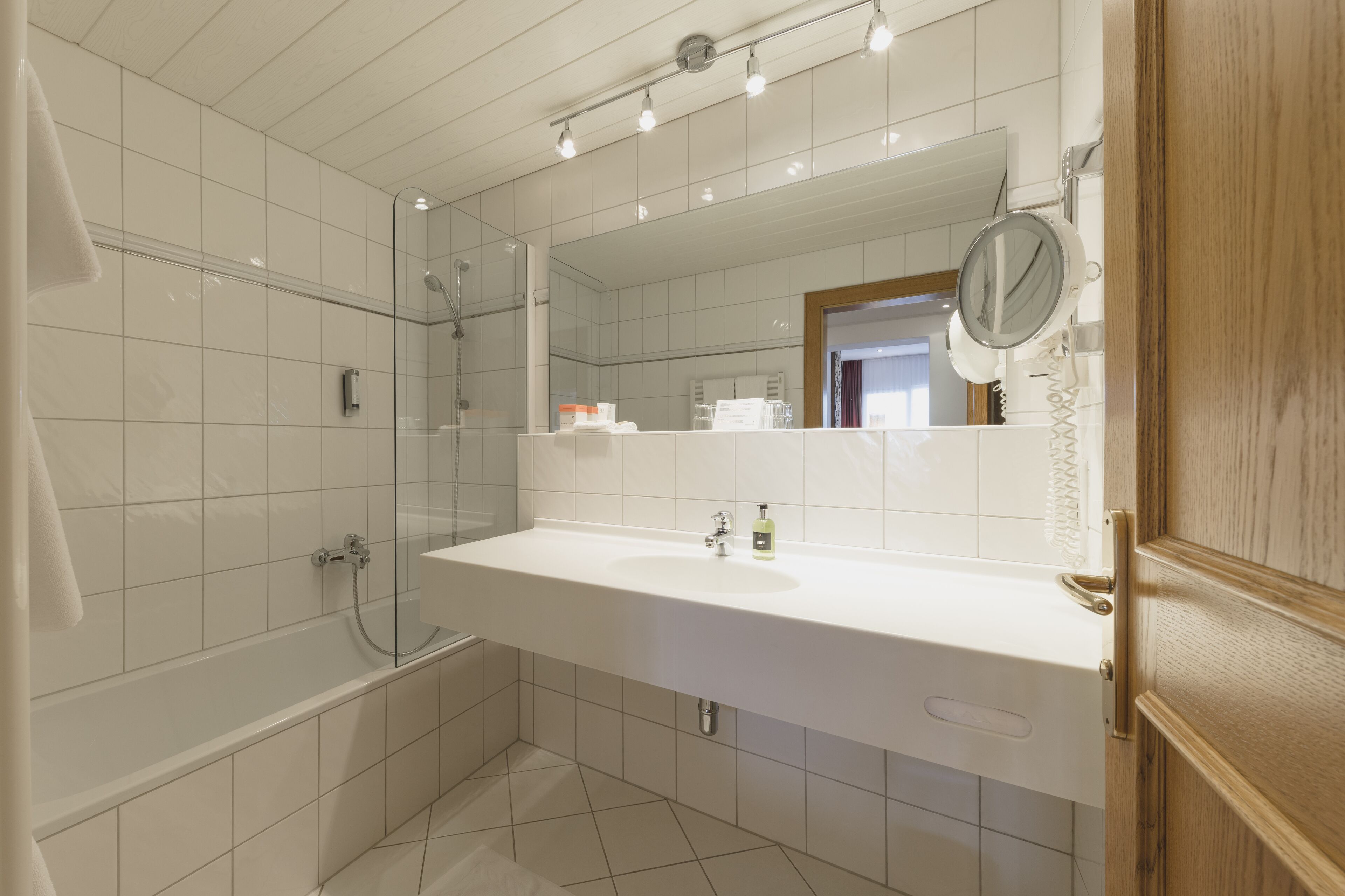 Ein modernes Badezimmer mit einem großen Spiegel, einer Badewanne und einem Waschbecken.