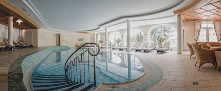 Una piscina techada, una piscina al aire libre, sombrillas