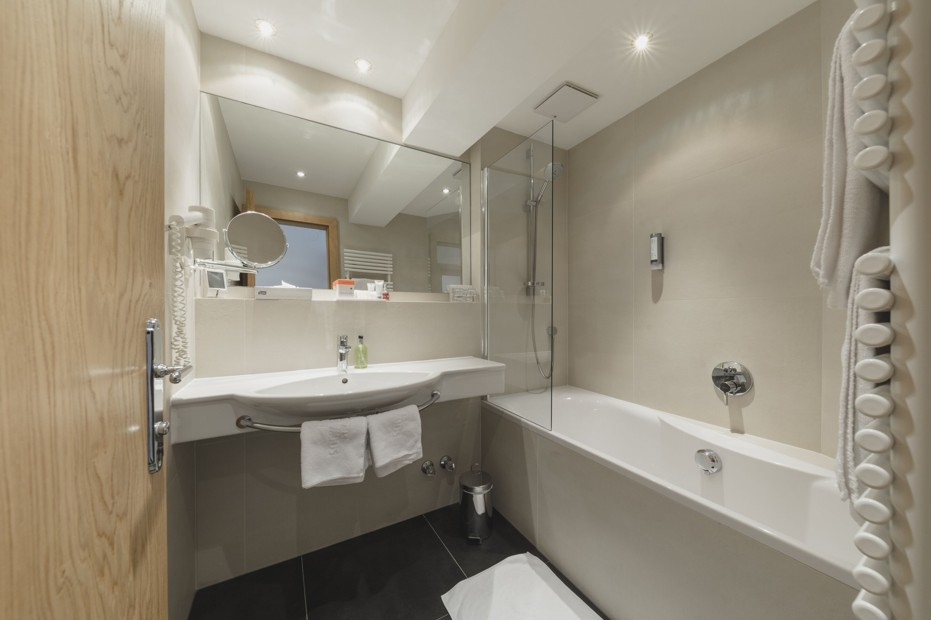 Un baño moderno con tocador, lavabo, espejo y bañera.
