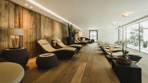 Un área de spa con paredes de madera, varias sillas reclinables y un ventanal con vistas al exterior.