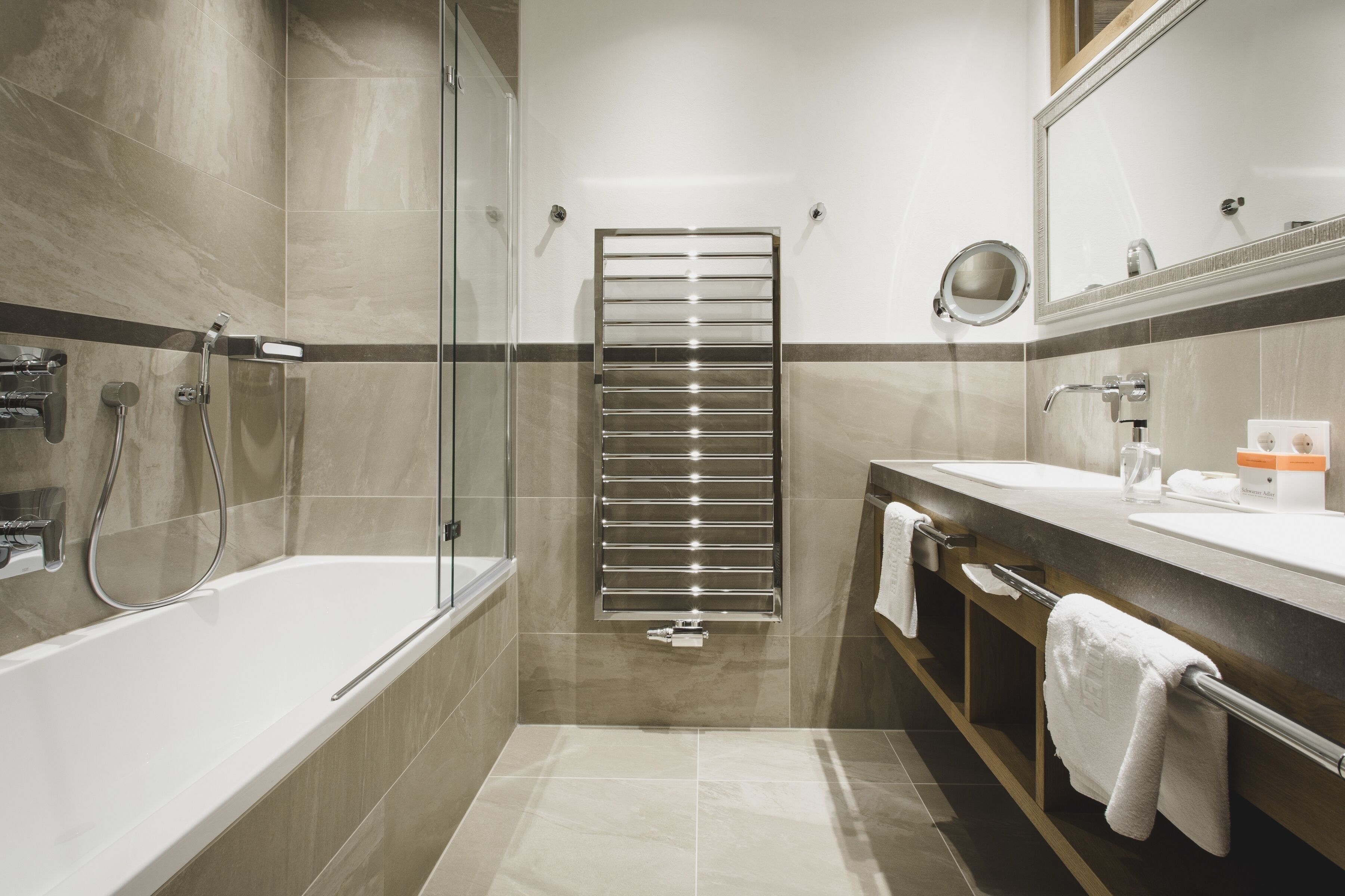 Un baño moderno con ducha de vidrio, una bañera grande y un tocador con espejo y toallero.