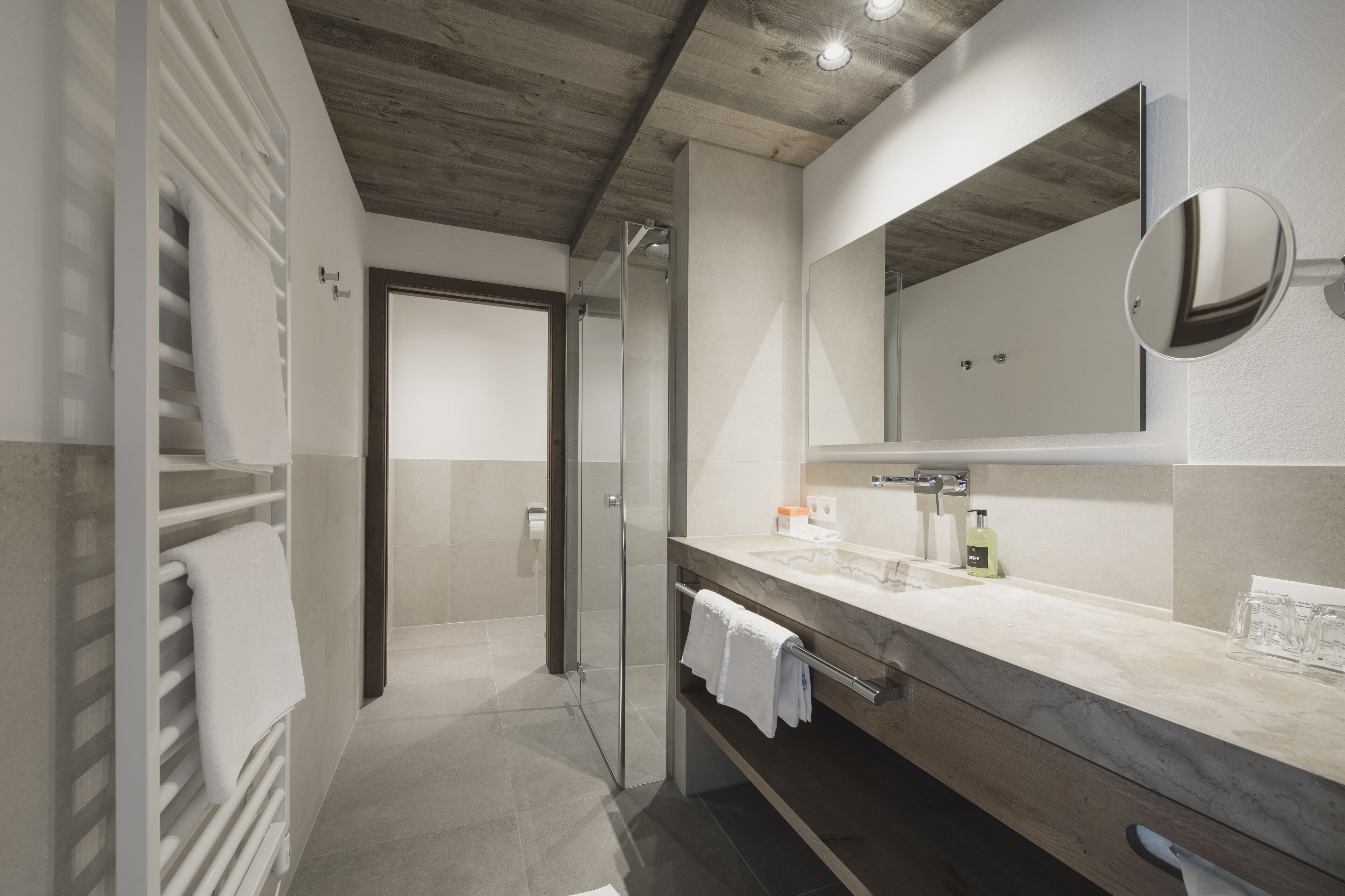 A modern bathroom with a glass shower, a marble vanity, and a large mirror.