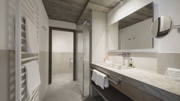 A modern bathroom with a glass shower, a marble vanity, and a large mirror.