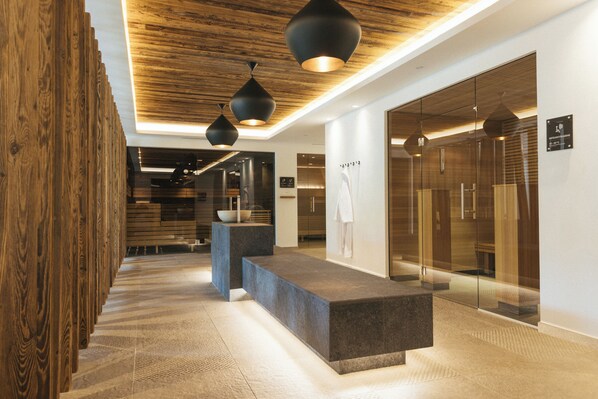 A modern reception area with a wooden reception desk, black pendant lighting, and a glass elevator.