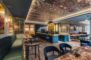 A modern restaurant interior with a bar area, seating arrangements, and decorative ceiling. - Löwen Hotel Montafon (Schruns)