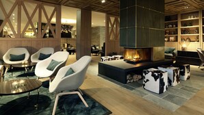 A modern living room with a large fireplace, comfortable seating, and a wooden ceiling.