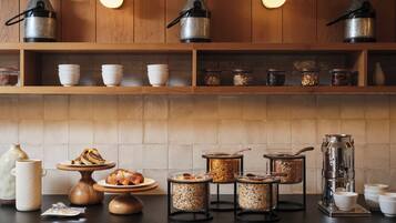 A kitchen with wooden cabinets, metal coffee pots, and various food containers.