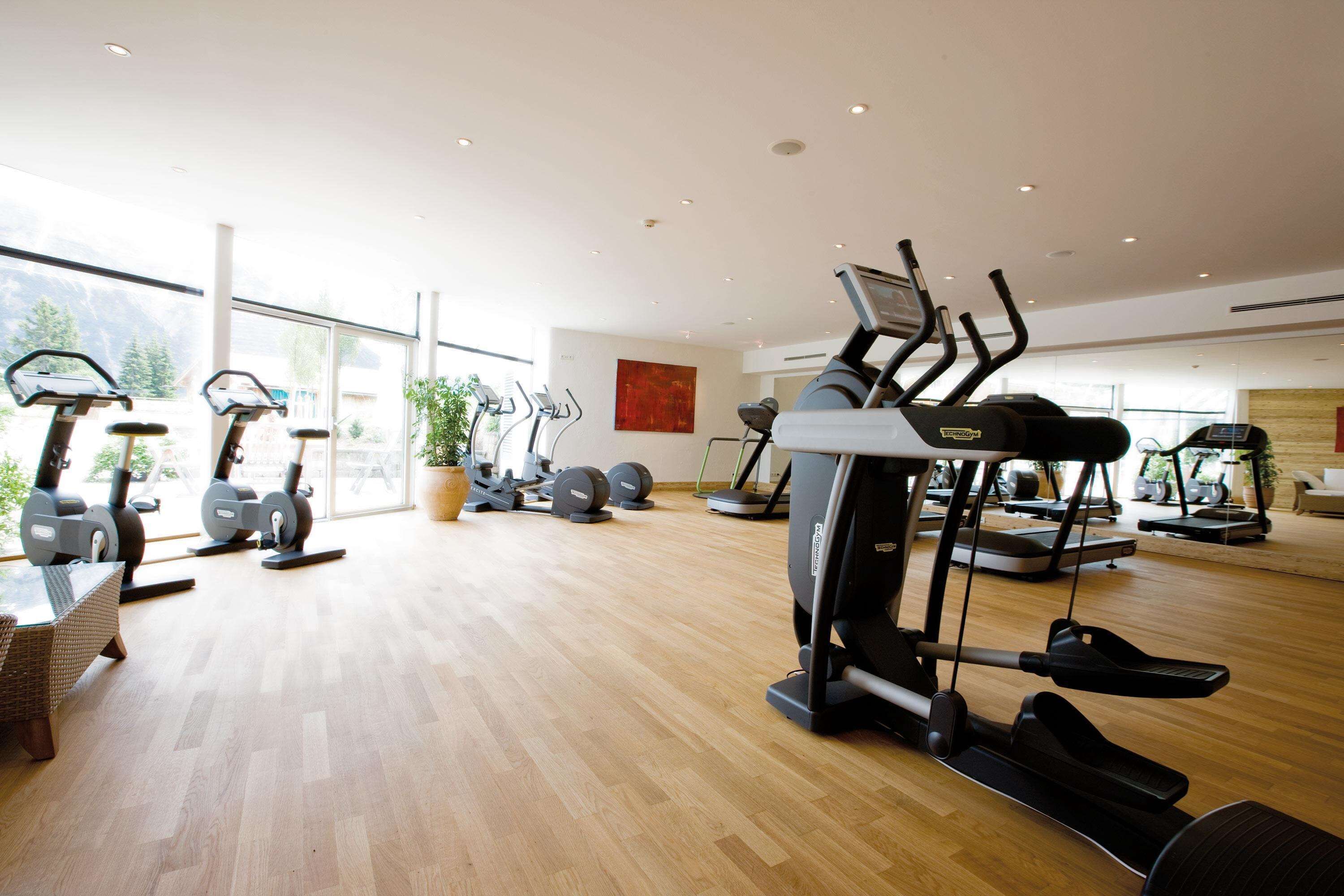 Een ruime fitnessruimte met diverse loopbanden, hometrainers en krachtapparaten.