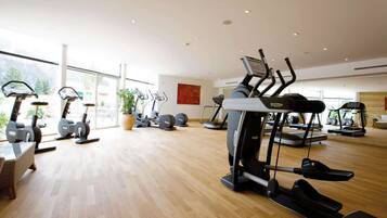 Een ruime fitnessruimte met diverse loopbanden, hometrainers en krachtapparaten.