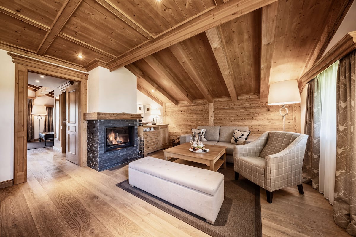 A spacious living room with a fireplace, wooden ceiling beams, a sofa, and a coffee table.