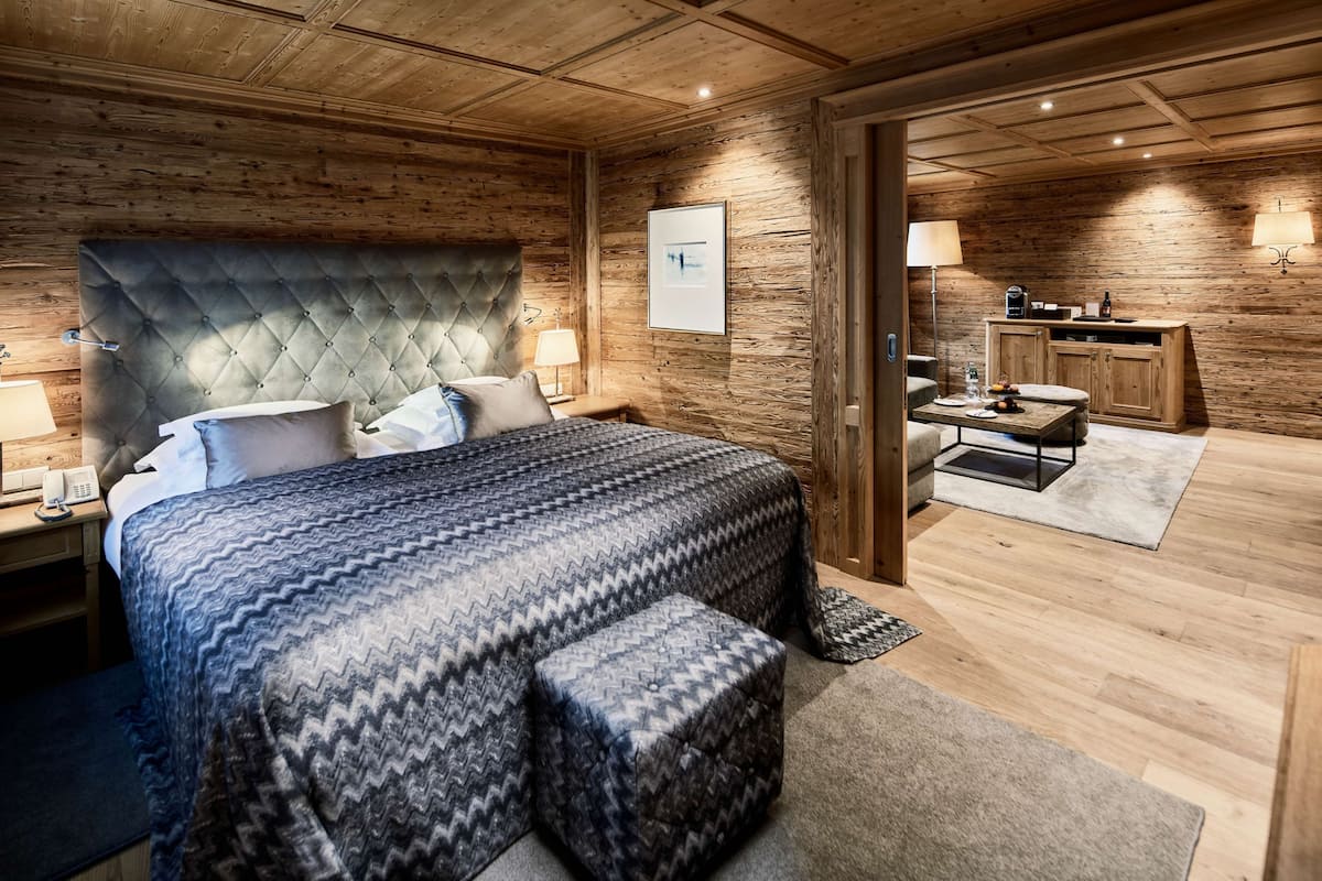 A bedroom with a large bed, a wooden headboard, bedside lamps, and a nightstand.