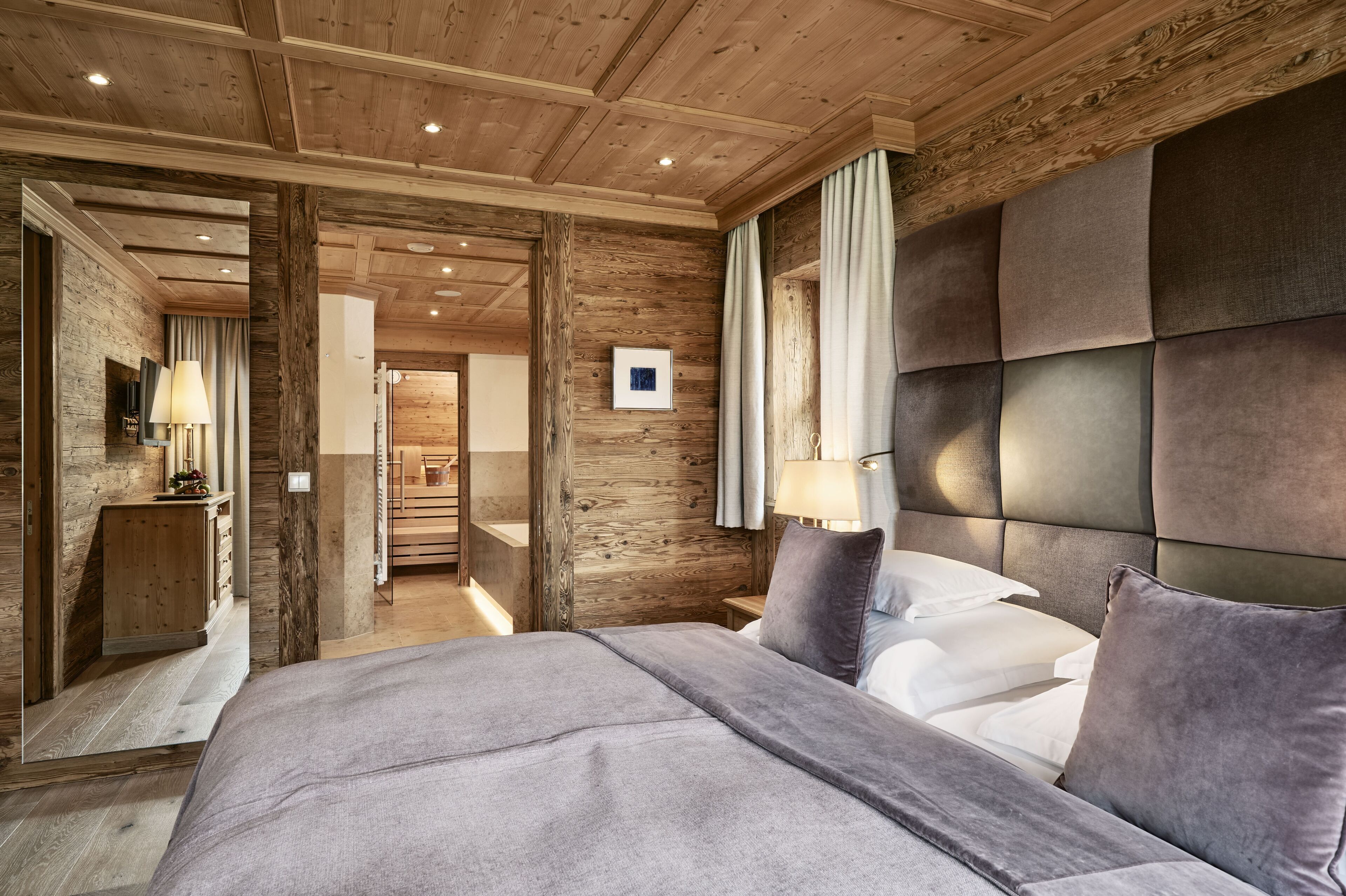 A bedroom with a large bed, wooden panel walls, and a modern headboard.