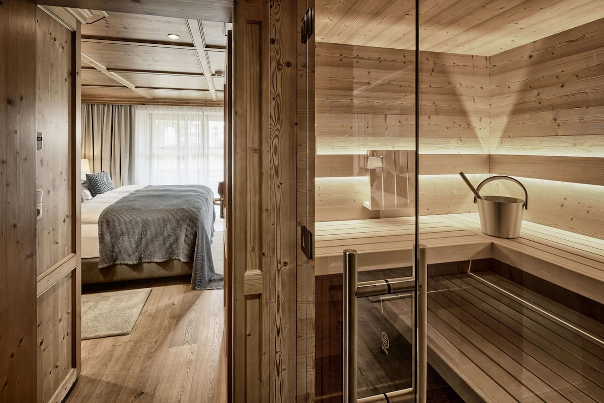 A wooden interior with a bed, a sauna, and a glass door.