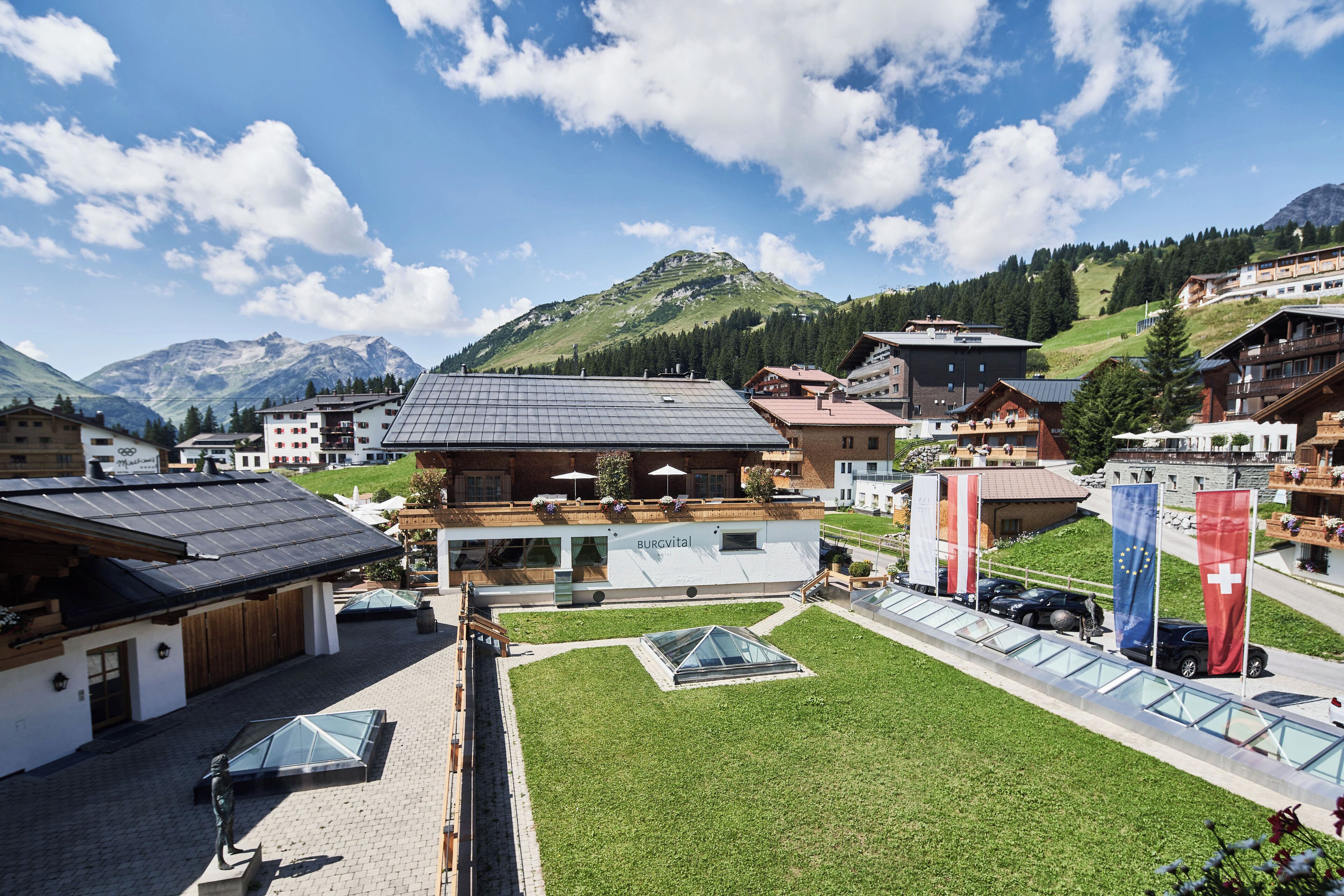 A hotel with a modern design, a rooftop terrace, and a view of the surrounding mountains.