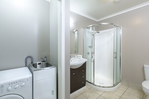Un baño moderno con ducha de vidrio, lavamanos integrado y lavadora.