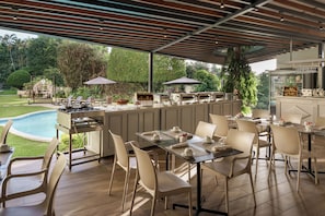 Un espace extérieur aménagé pour les repas, avec une piscine, des coins salon couverts et un espace barbecue.