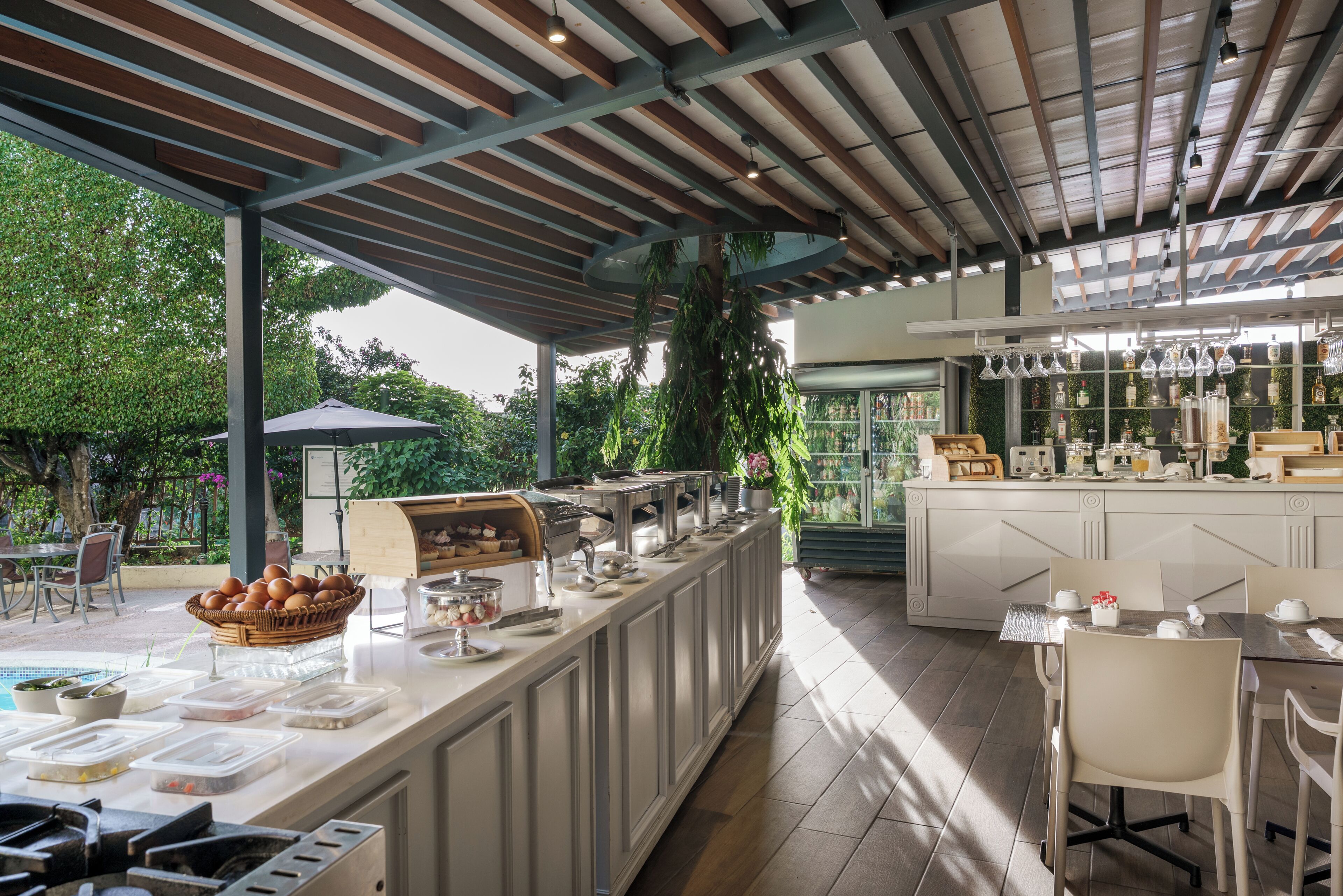 A covered outdoor dining area with a buffet, seating, and a bar.