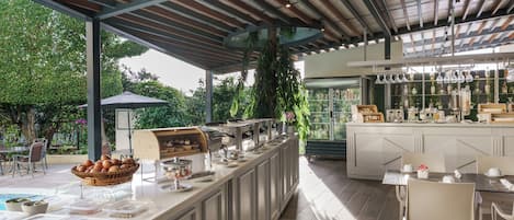 A covered outdoor dining area with a buffet, seating, and a bar.
