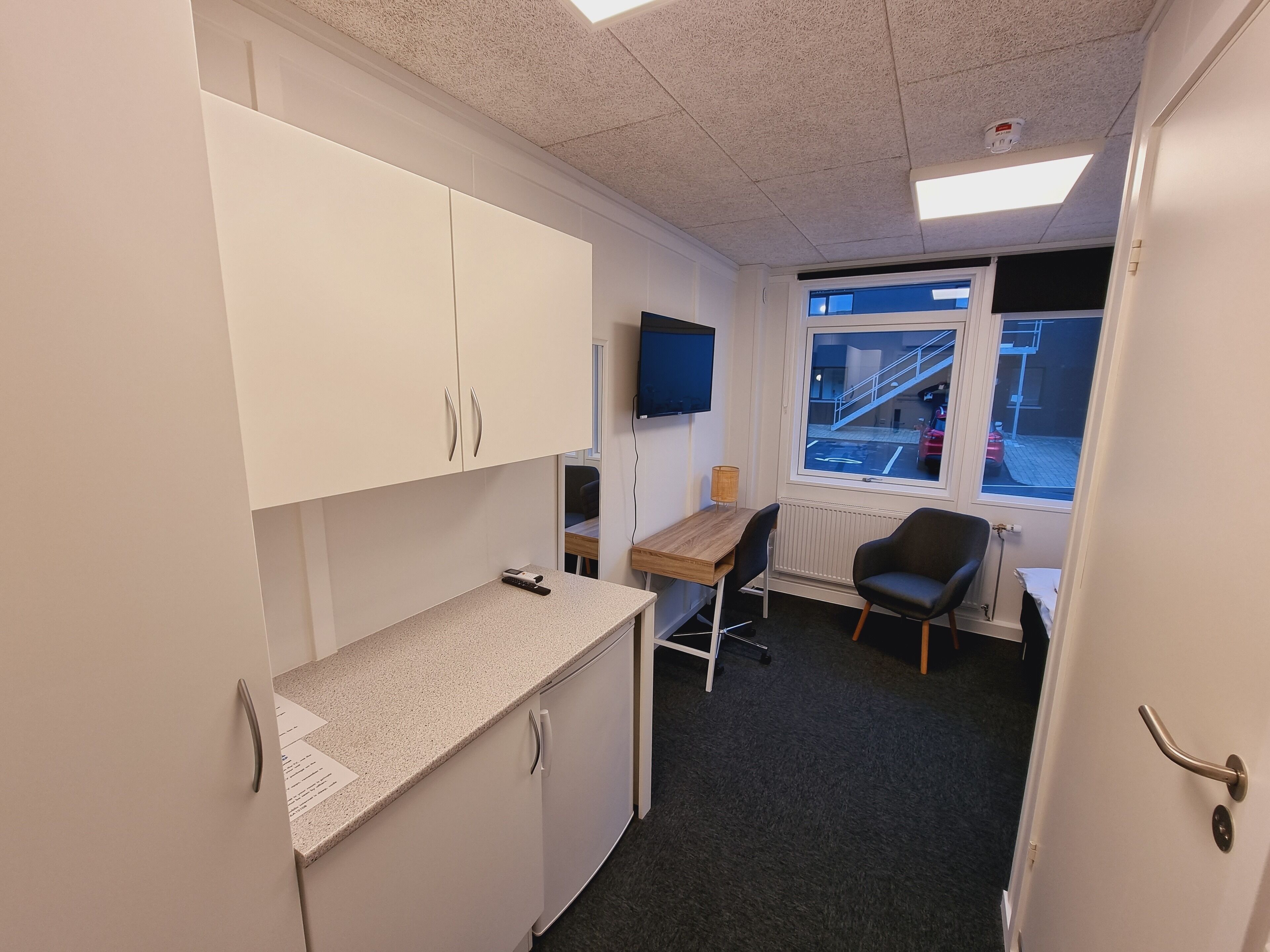 A small office space with a desk, chair, and a television mounted on the wall.