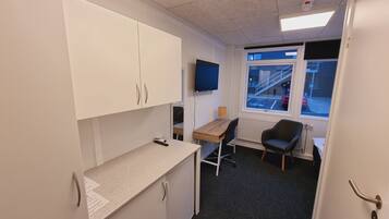 A small office space with a desk, chair, and a television mounted on the wall.