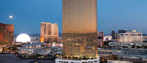 A high-rise hotel with a prominent 'TRUMP' sign, surrounded by other buildings and a parking area.